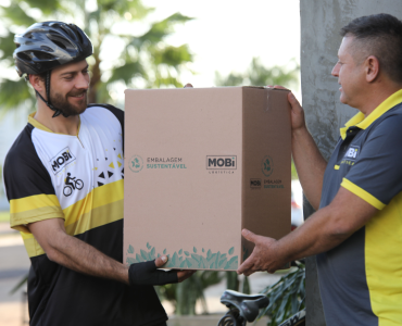 Funcionário da Mobi Logística entregando caixa sustentável ao entregador ciclista da Mobi.