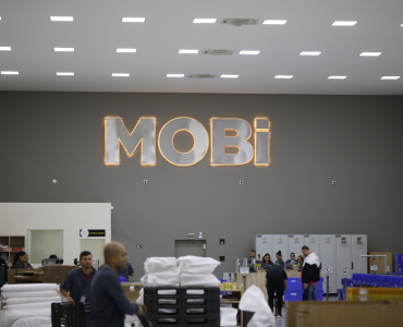 Galpão da Mobi Logística, com o logo grande da empresa na parede ao fundo.
