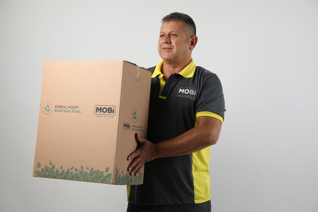 Funcionário da Mobi Logística em fundo branco, segurando uma caixa grande da Mobi.