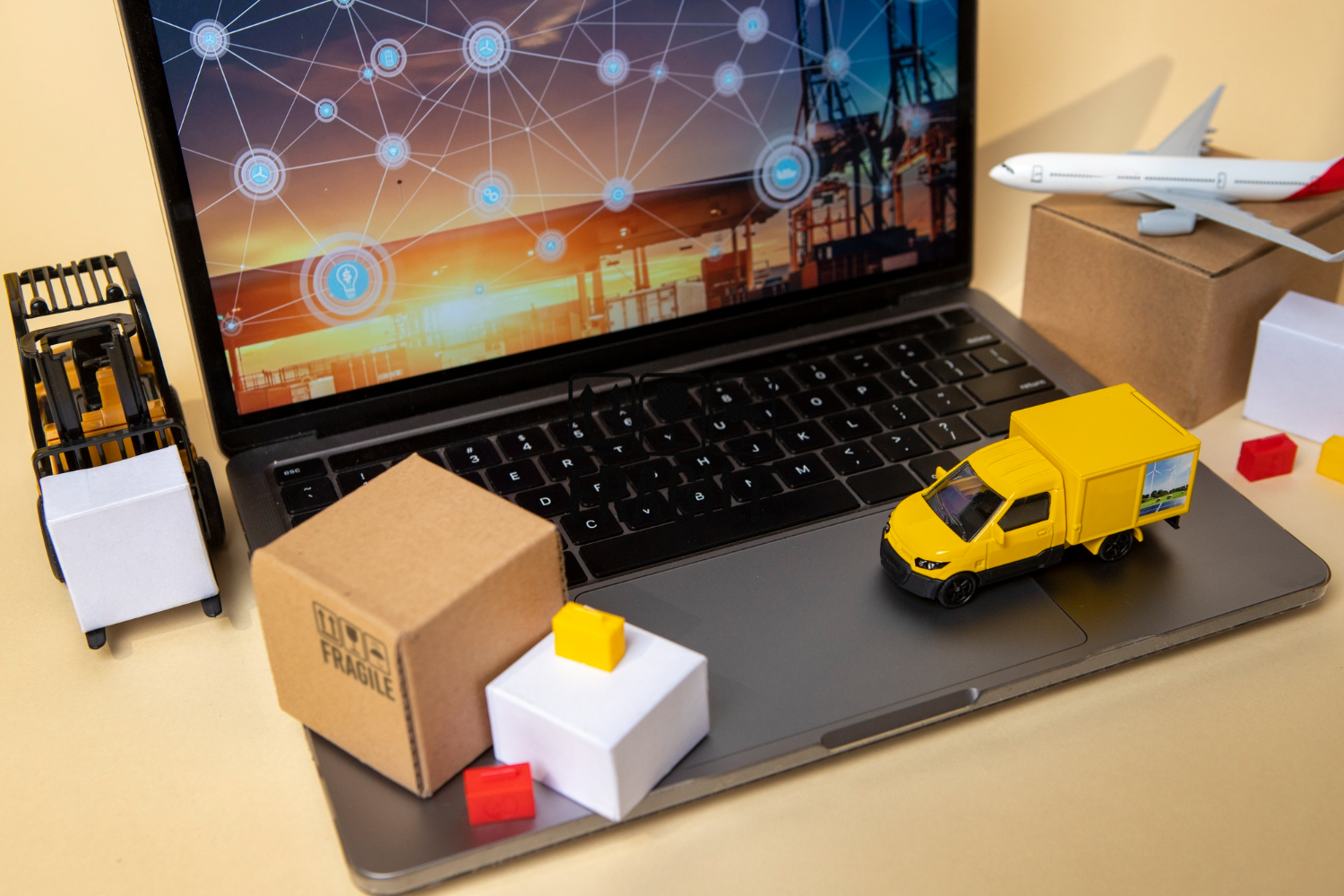 Laptop aberto sobre uma mesa, com ilustrações em 3D de veículos e objetos, como caixas, que representam o setor da logística. 